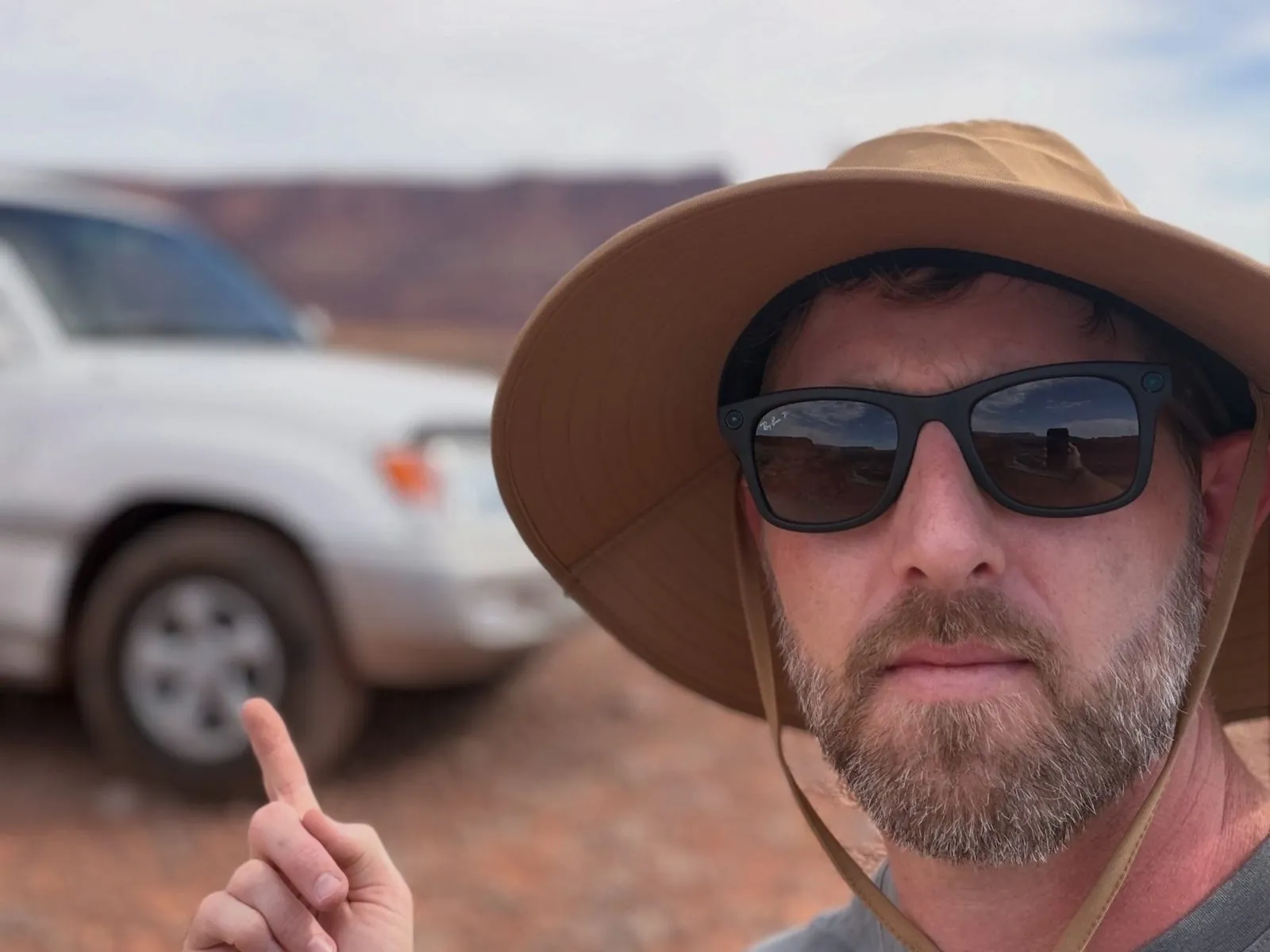 Jake Tiesler pointing at a silver 100 Series Land Cruiser in the desert