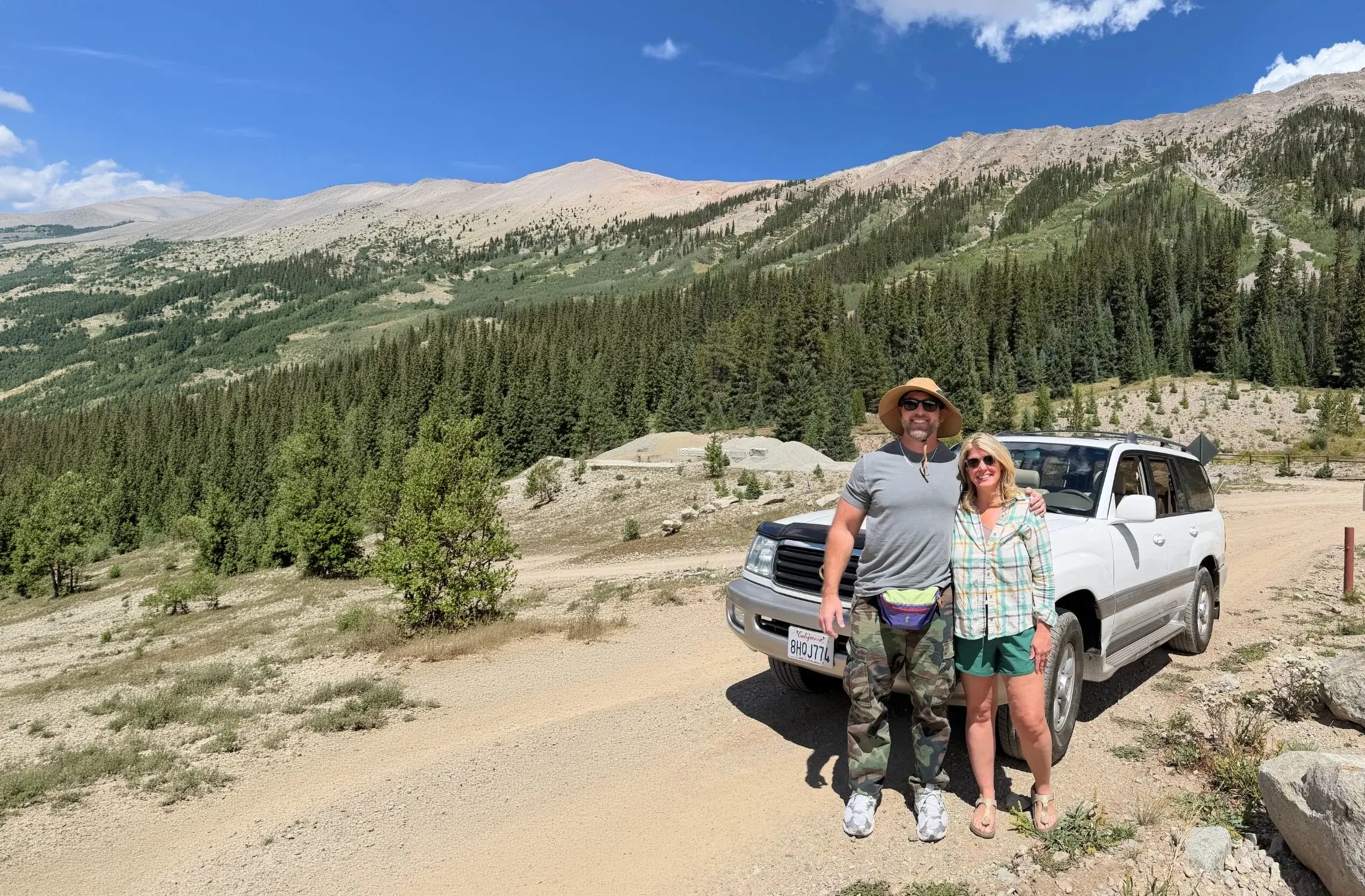 Jake Tiesler and a friend standing in front of a white 100 Series Land Cruiser on a mountain road